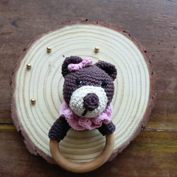 a bear rattle on a wood coaster with pink ruffle