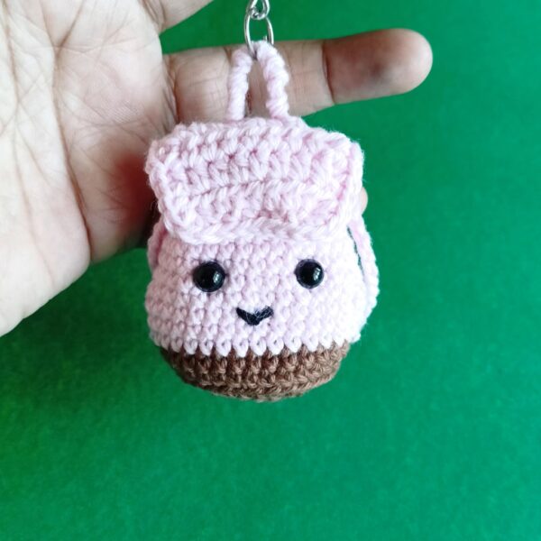 Handmade crochet mini backpack keychain on a green background