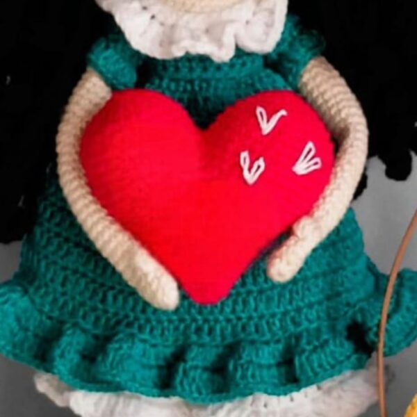 a crocheted heart in a dolls hand