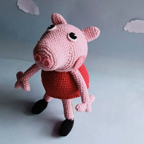 an amigurumi peppa pig in a blue background